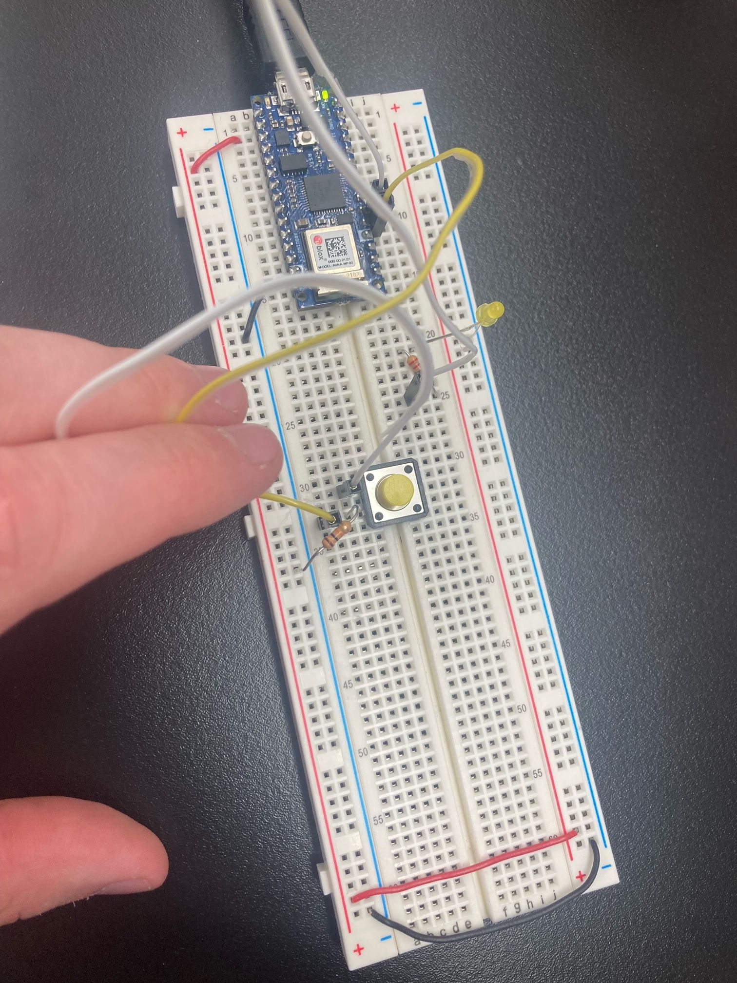 A breadboard with a pushbutton wired to an Arduino Nano as a digital input and output to LED.
